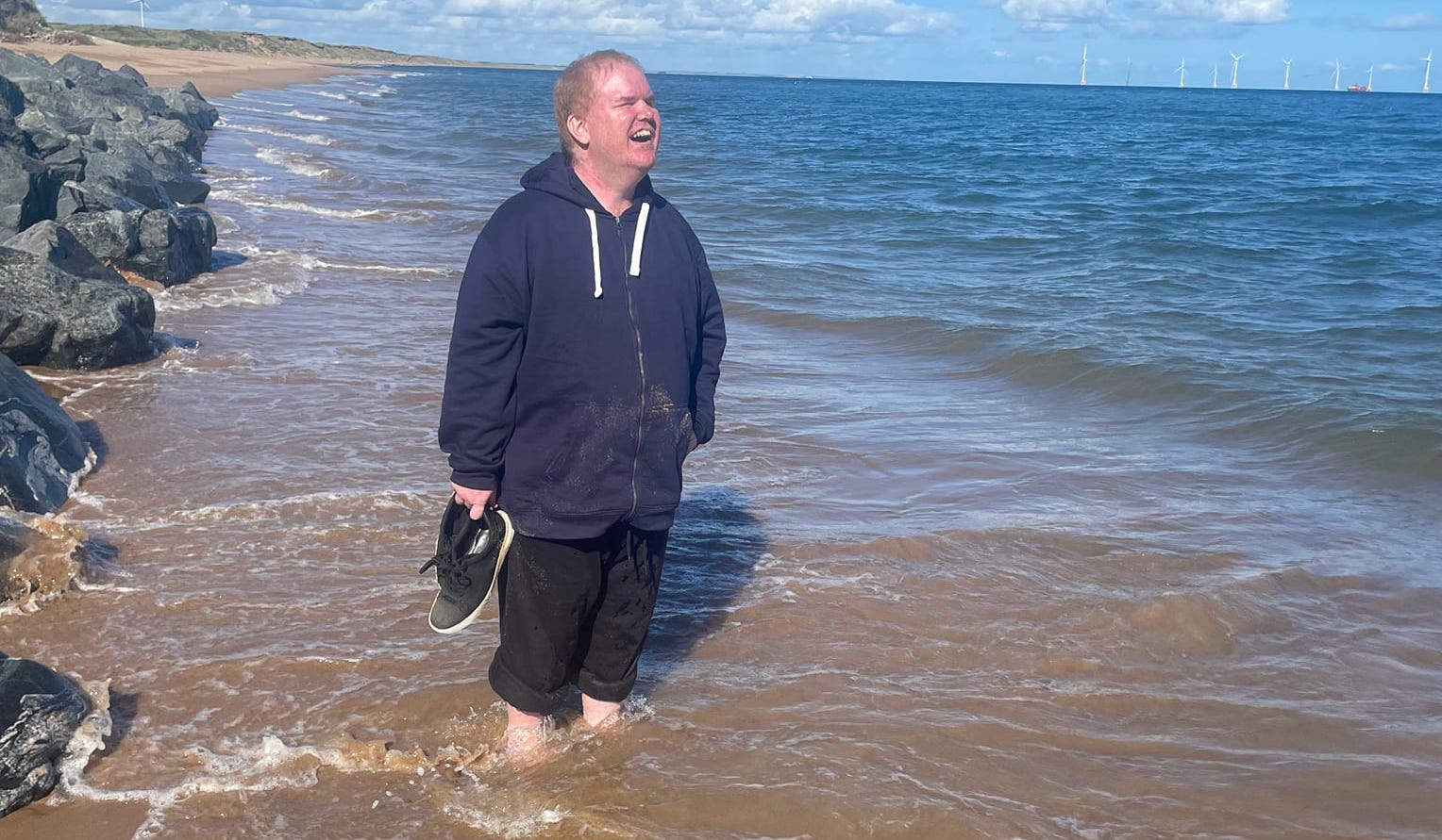 Andrew standing in the sea in Scotland grinning