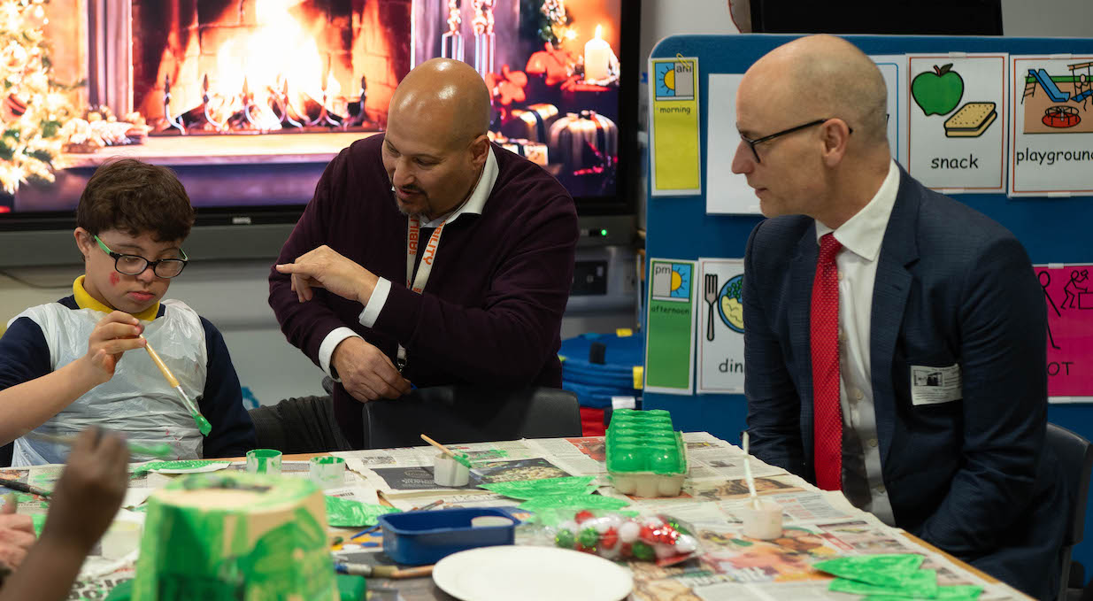 A Dispensing Optician shows Stephen Kinnock the glasses of a boy who is painting