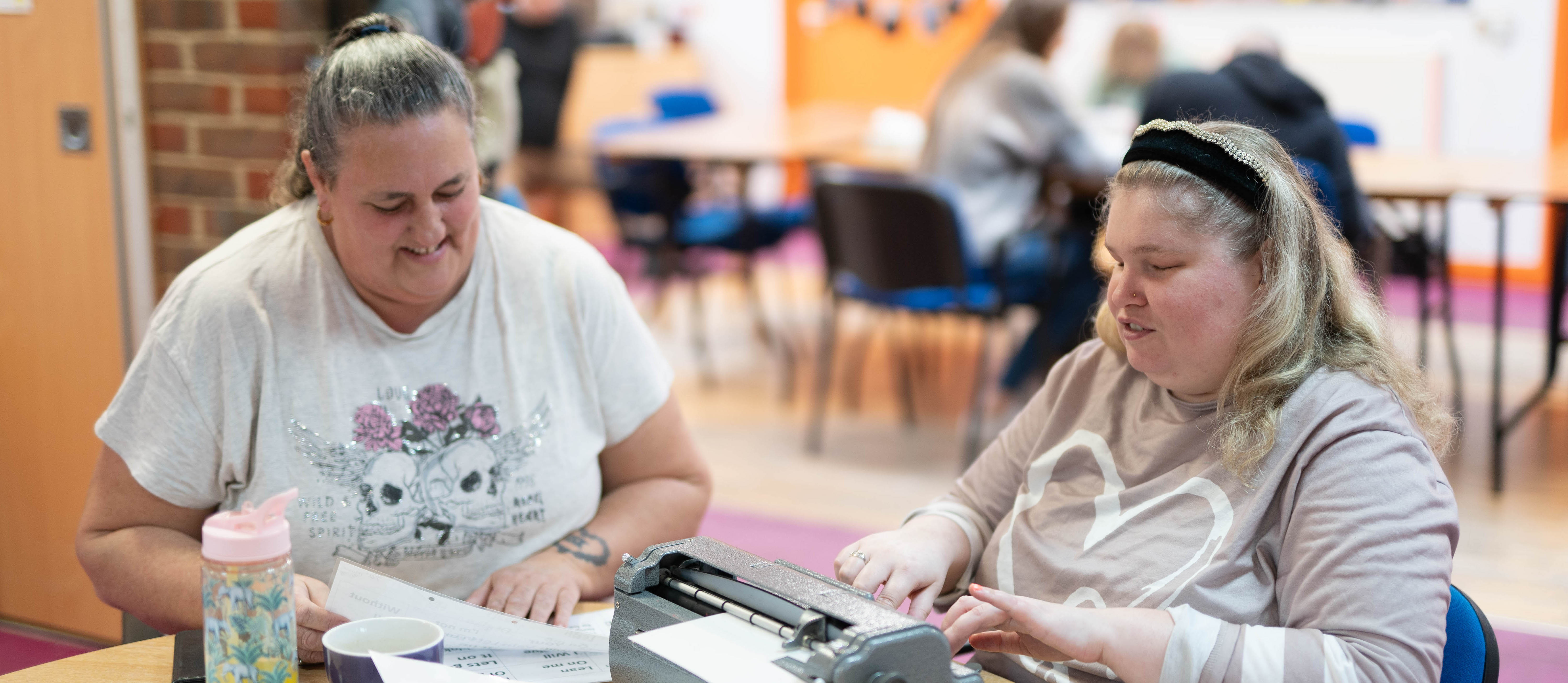 Joanne being supported to use a Braille machine