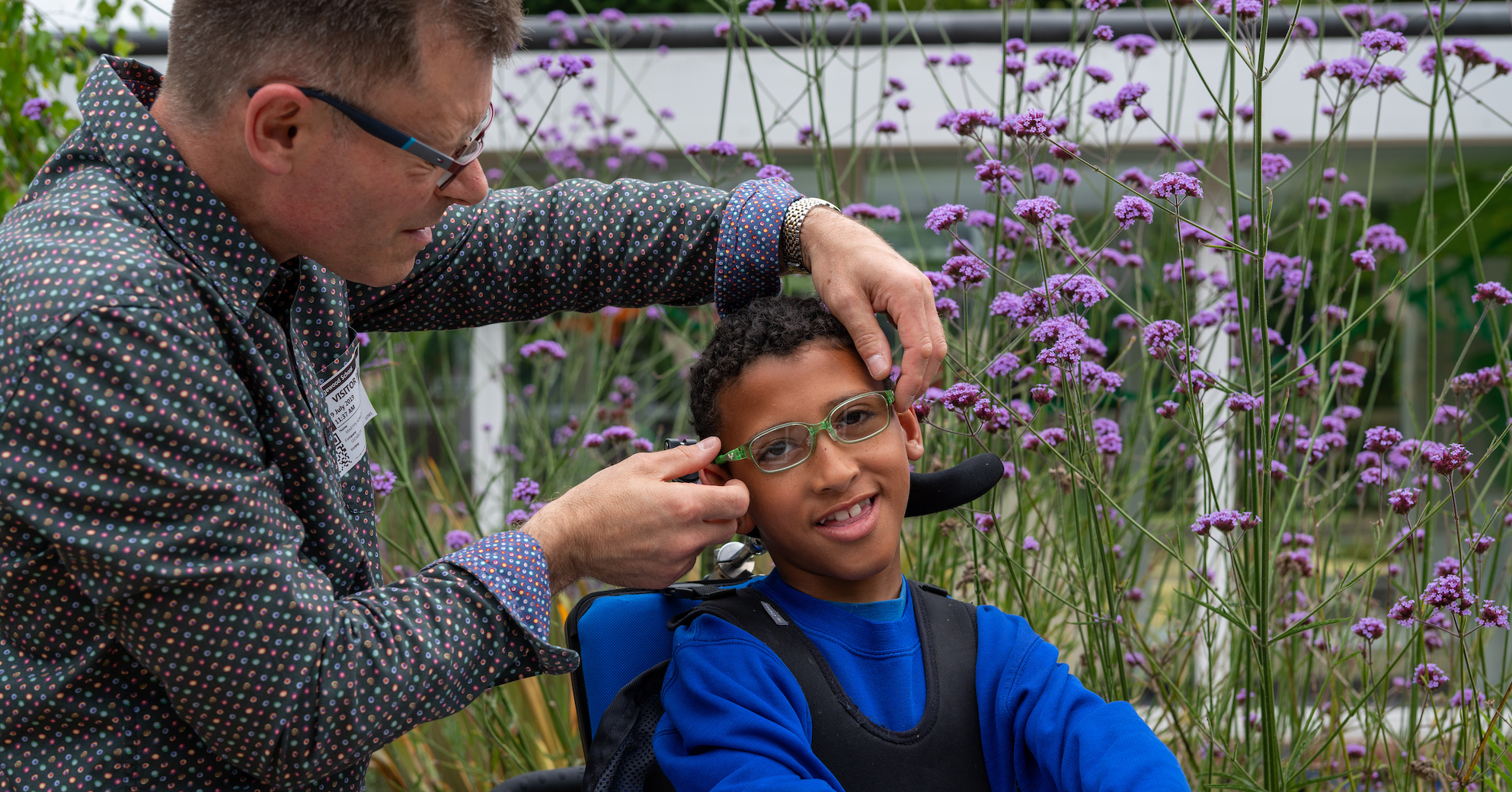 Martyn fits a pair of glasses on Eli, a young boy with a wheelchair