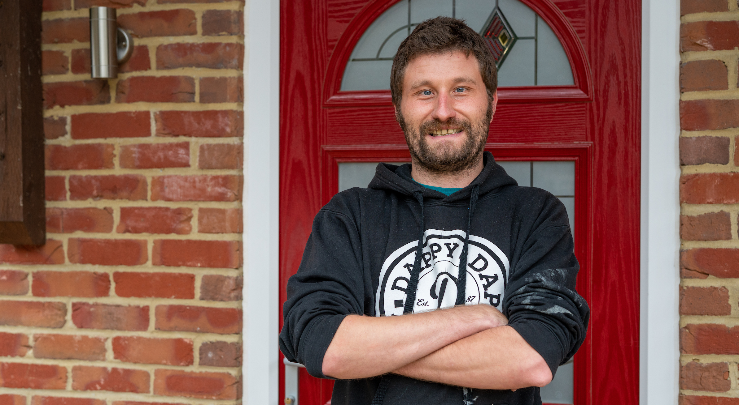 Shane stands outside his front door, looking proud