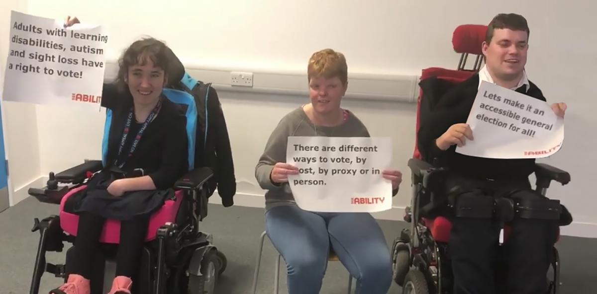 Emily and her colleagues hold up signs asking for disability equality in the last election