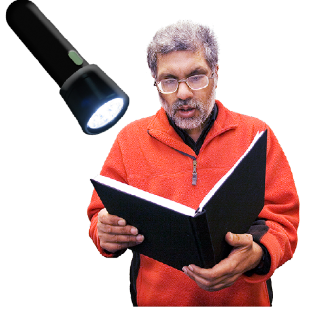 A person reading a book with a torch