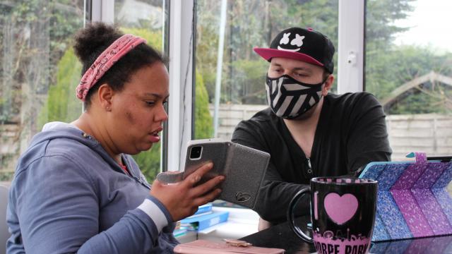 A support worker helps someone with their phone.