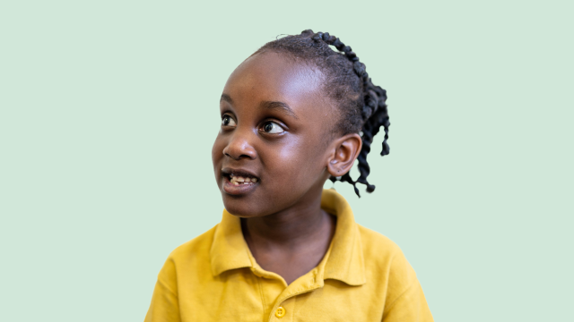 Helen, a young girl in school uniform, in front of a green backdrop.