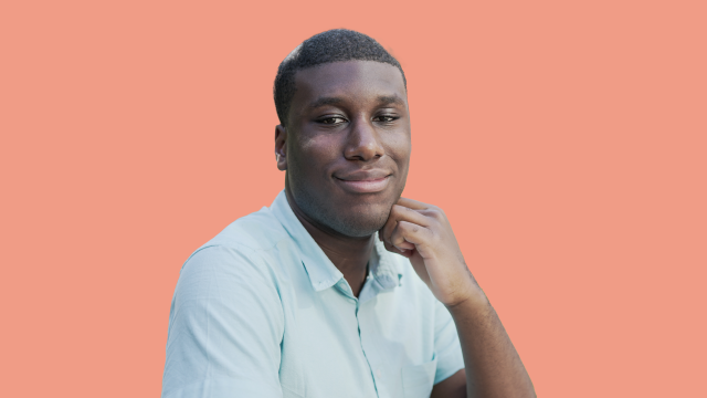 Lance leaning on his hand in front of an orange backdrop