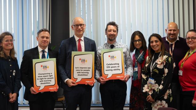 Stephen Kinnock MP with teachers and the eye test team, holding up signs that promote the service